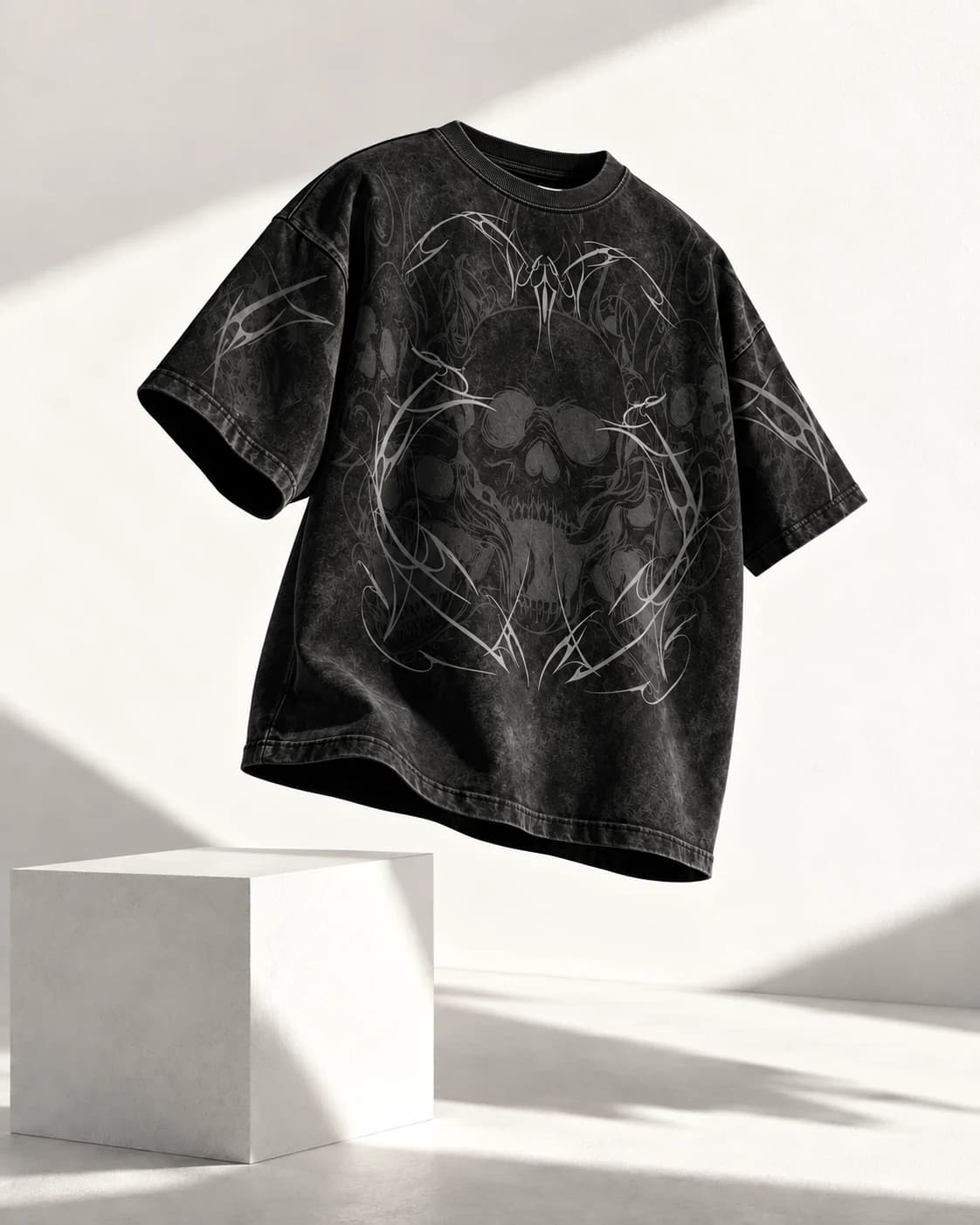 The front of a black skull and tribal-print tee floating above a white architectural block